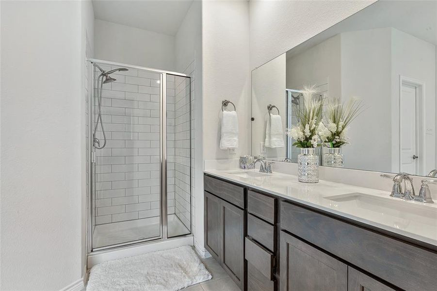 Bathroom featuring tile floors, a shower with door, and double sink vanity