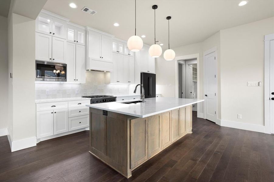 Kitchen with white cabinets, stainless steel appliances, sink, dark hardwood / wood-style floors, and an island with sink