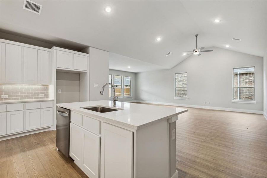 Kitchen with an island with sink, light hardwood / wood-style floors, sink, and ceiling fan