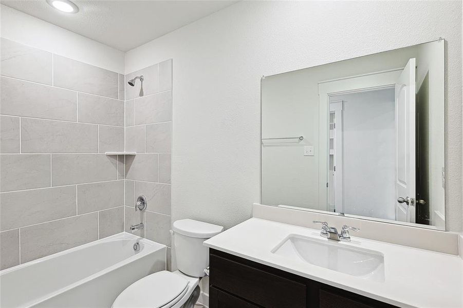 Full bathroom with tiled shower / bath, toilet, and vanity