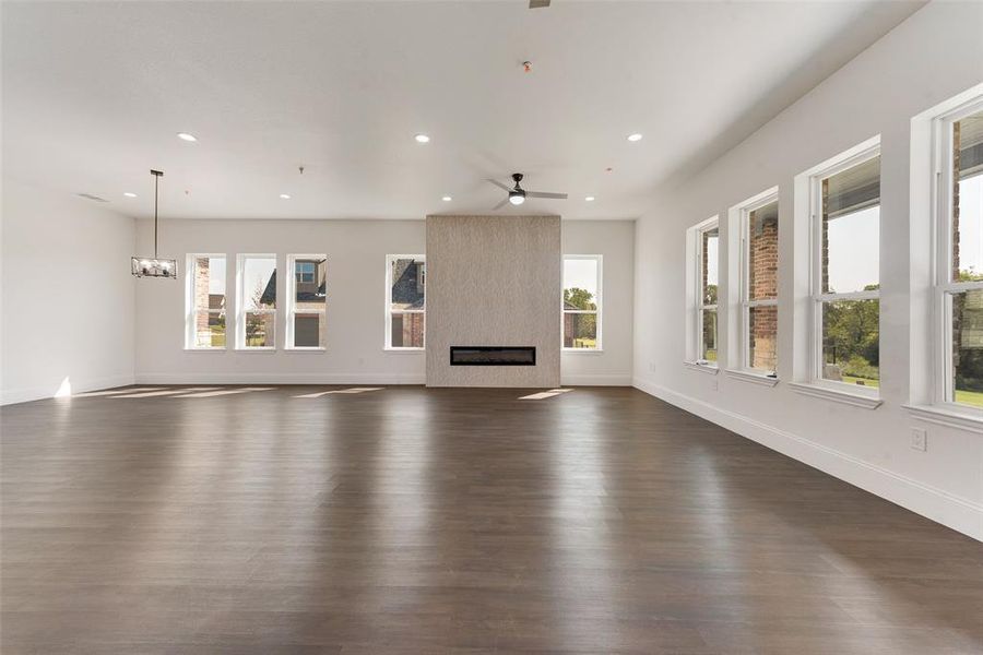 Unfurnished living room featuring ceiling fan, a fireplace, and dark hardwood / wood-style flooring