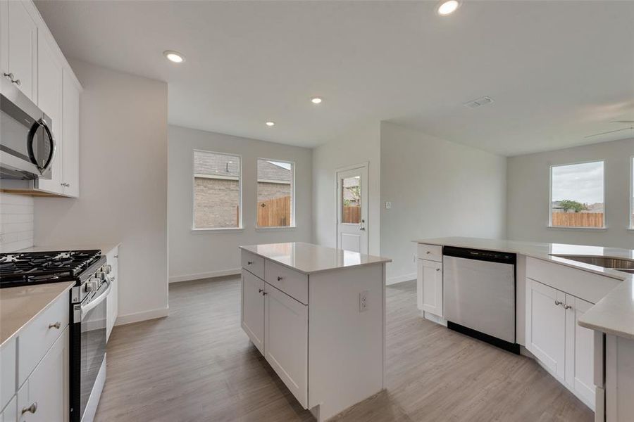 Kitchen featuring a center island, appliances with stainless steel finishes, light hardwood / wood-style floors, and white cabinetry