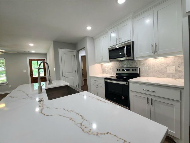 Kitchen featuring stainless steel appliances and kitchen island with farmhouse sink