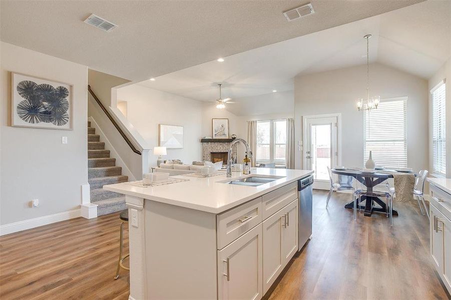 Kitchen featuring pendant lighting, dishwasher, hardwood / wood-style flooring, sink, and an island with sink