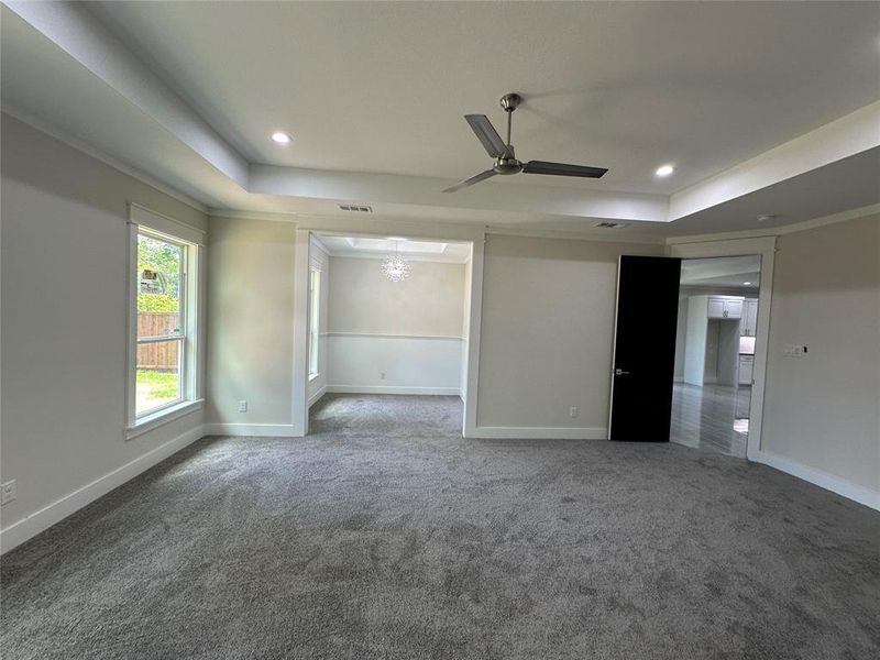 Master Bedroom with attached office featuring ceiling fan, a raised ceiling, and dark carpet