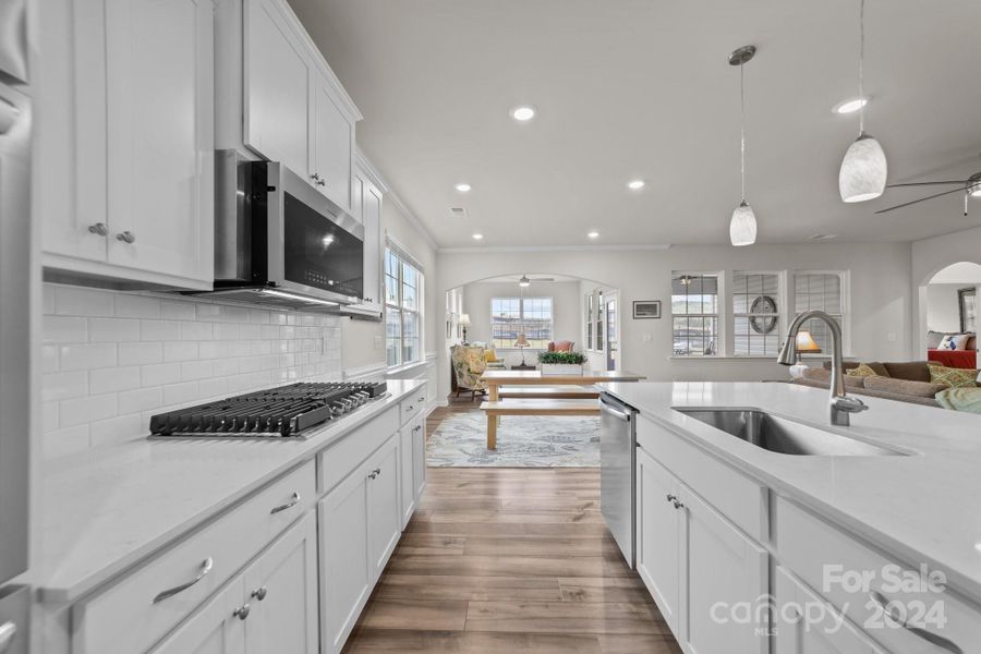 Grand view from kitchen across breakfast area to keeping room. Open floor plan and high ceilings, recessed and pendant lighting and a smooth neutral color combination throughout this home.