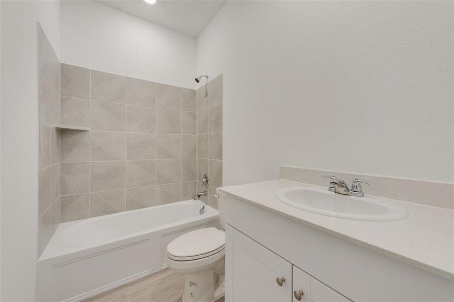 Full bathroom featuring hardwood / wood-style floors, vanity, toilet, and tiled shower / bath combo