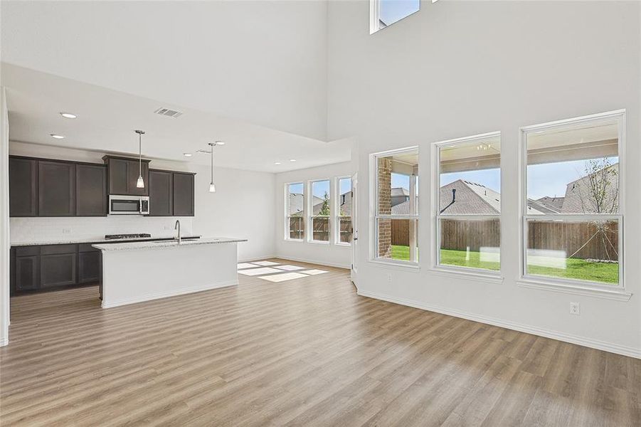 Unfurnished living room featuring light hardwood / wood-style floors, sink, and a high ceiling