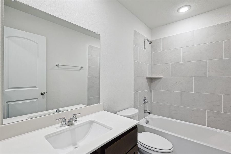 Full bathroom featuring tiled shower / bath, vanity, and toilet