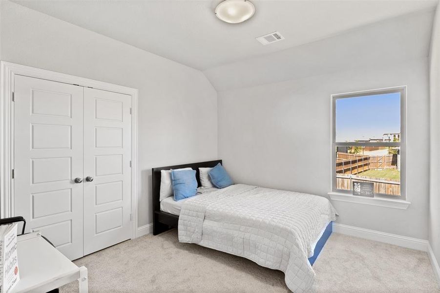 Carpeted bedroom featuring lofted ceiling and a closet