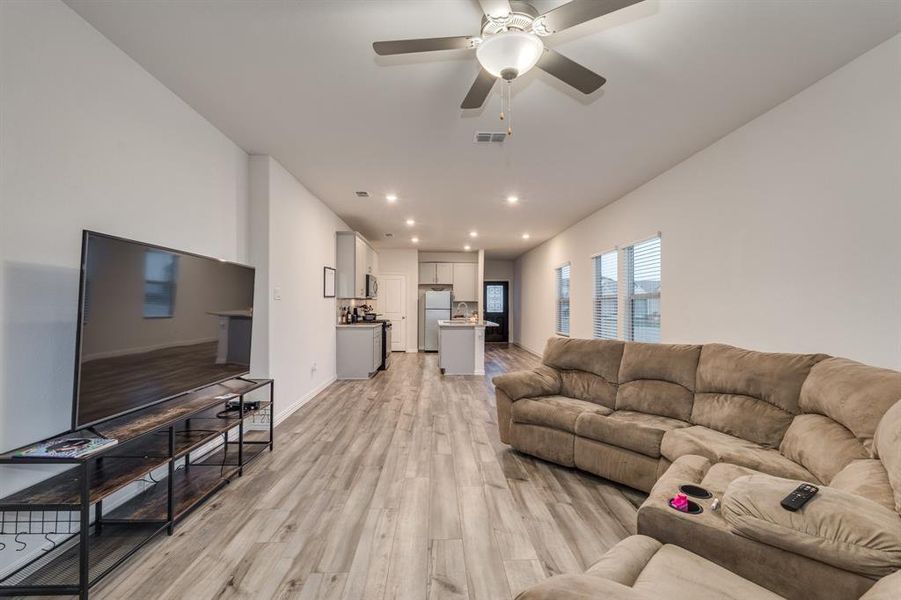 Living room with ceiling fan and light hardwood / wood-style floors