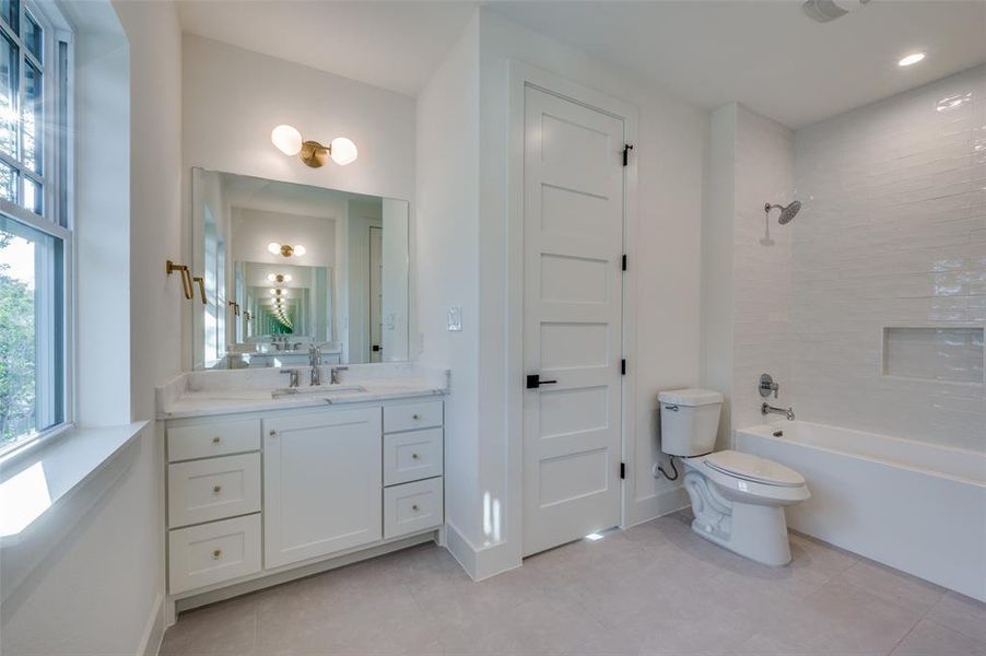 Full bathroom with tiled shower / bath combo, vanity, and toilet