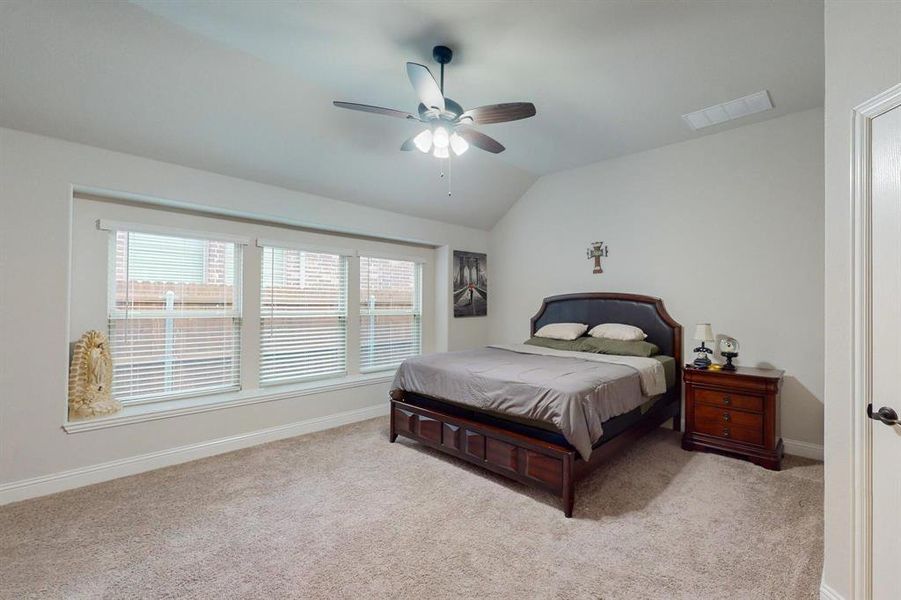 Carpeted bedroom featuring ceiling fan and vaulted ceiling