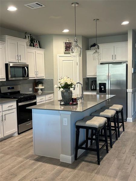 Kitchen featuring appliances with stainless steel finishes, white cabinetry, and a center island with sink