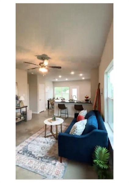 Living room with ceiling fan and concrete floors