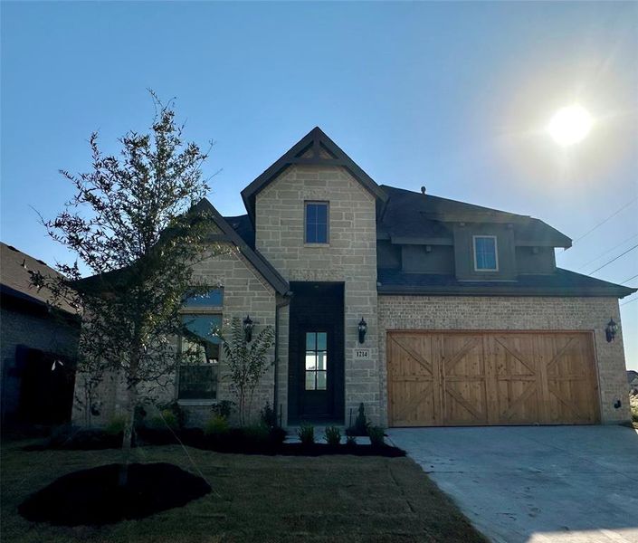 View of front facade featuring a front yard and a garage