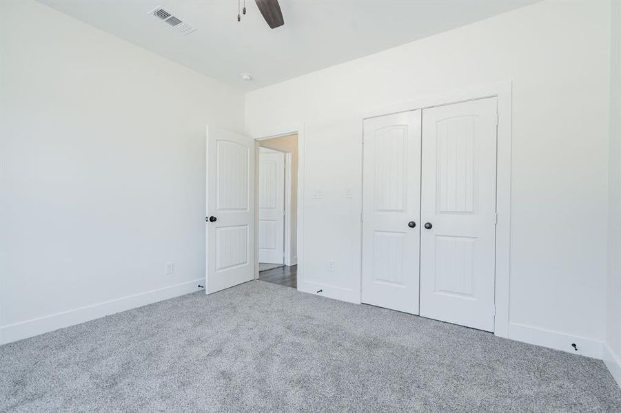 Unfurnished bedroom featuring carpet, ceiling fan, and a closet