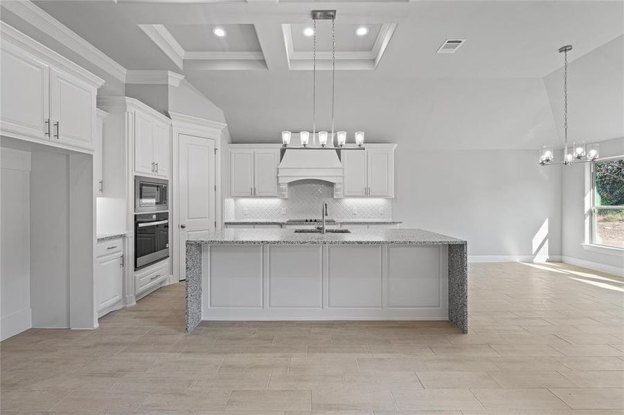 Kitchen with light stone countertops, appliances with stainless steel finishes, pendant lighting, and white cabinets