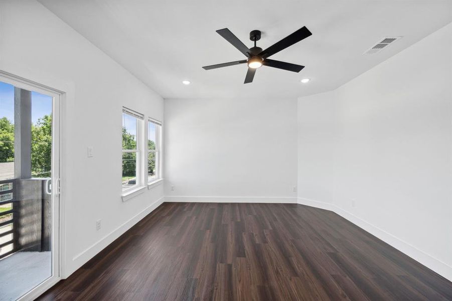 Empty room with dark hardwood / wood-style floors, plenty of natural light, and ceiling fan