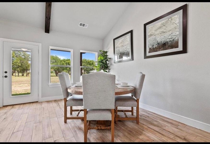 Dining area featuring light hardwood / wood-style flooring and vaulted ceiling with beams