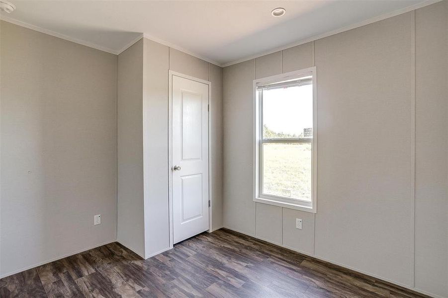 Unfurnished bedroom with dark wood-type flooring and crown molding