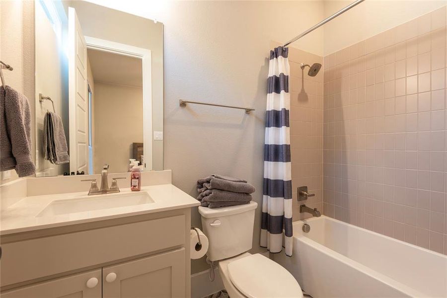 Full bathroom featuring vanity, toilet, and shower / bath combination with curtain