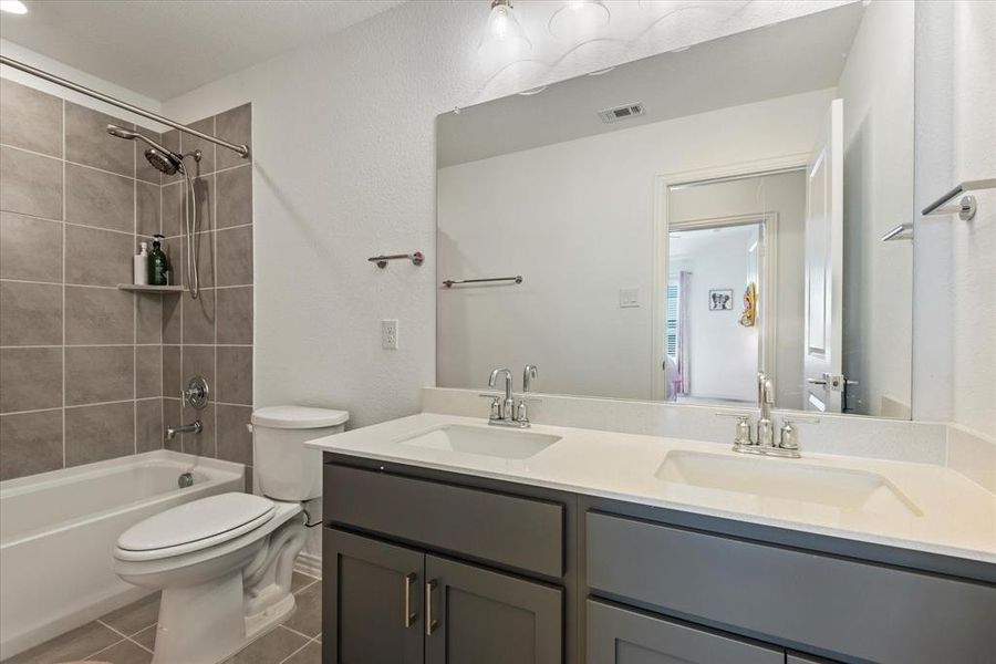 Full bathroom with toilet, tiled shower / bath, vanity, and tile patterned flooring