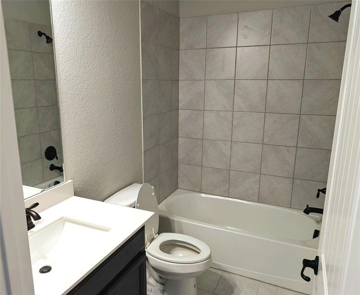 Full bathroom featuring tile patterned flooring, tiled shower / bath, toilet, and vanity