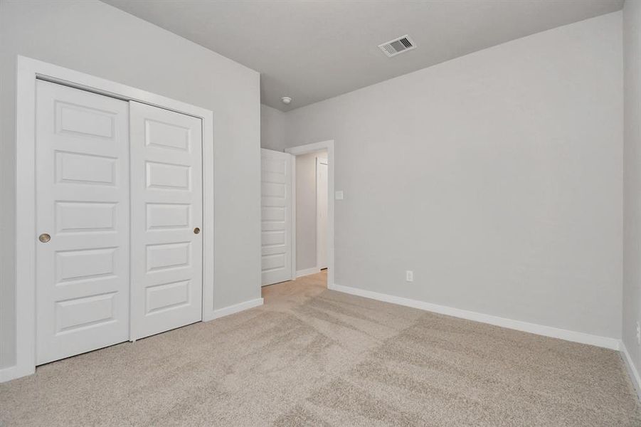 Generously sized secondary bedrooms, complete with spacious closets and soft, inviting carpeting. Enjoy abundant natural light streaming in through the large windows. Sample photo of similar plan. As-built color and selections may vary.