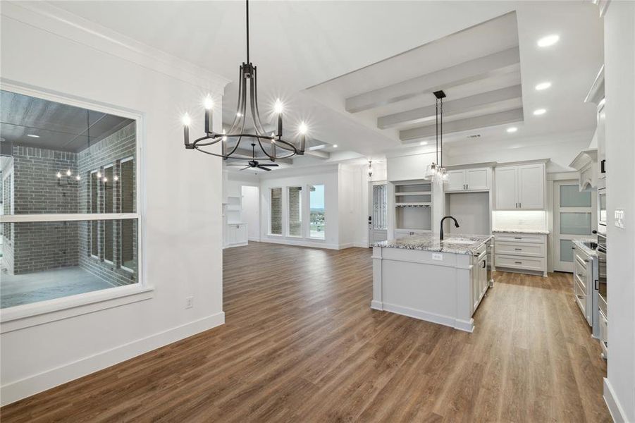 Kitchen with pendant lighting, light stone counters, and hardwood / wood-style floors