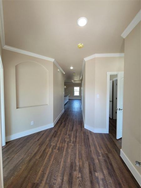 Empty room featuring dark hardwood / wood-style flooring and crown molding