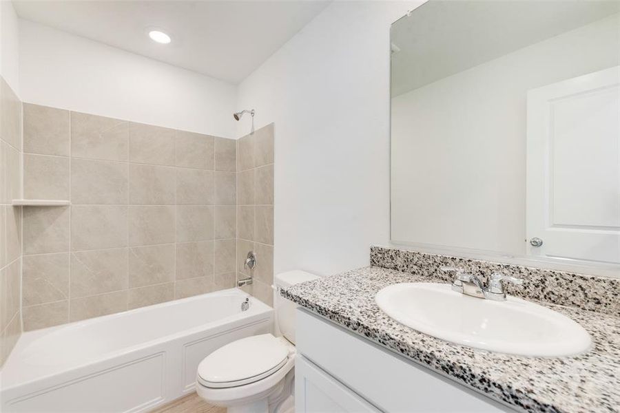 Full bathroom with toilet, vanity, and tiled shower / bath combo