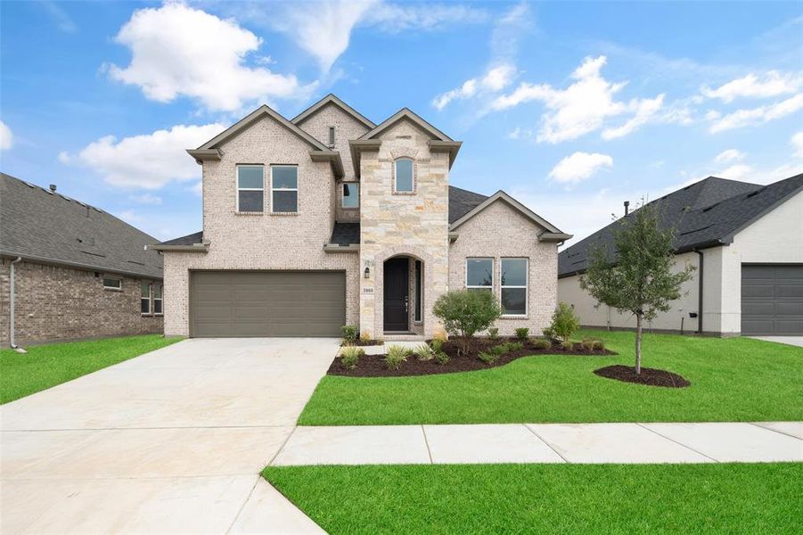 View of front facade featuring a garage and a front lawn