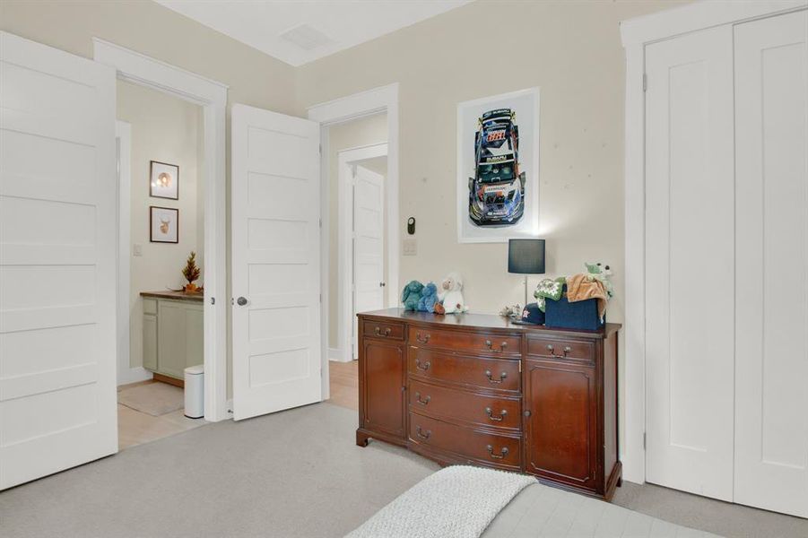 A different perspective of a well-maintained secondary bedroom with neutral walls and carpeted flooring. There are multiple doors offering convenient access to closet space.