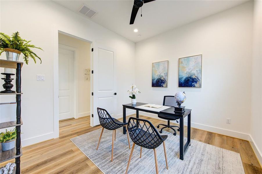 Guest Bedroom 1 (staged as an Office). All bedrooms feature LVP flooring, recessed LED lights, sleek black ceiling fans and large walk-in closets.