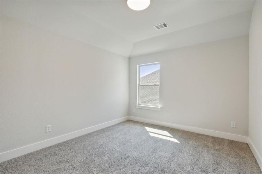 Carpeted empty room with vaulted ceiling