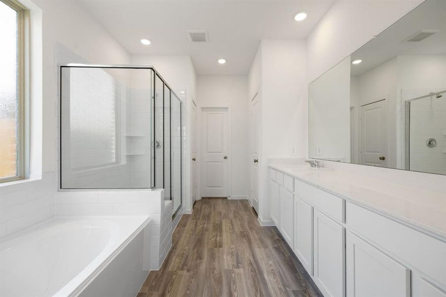 This primary bathroom is definitely move-in ready! Featuring white stained cabinets with light countertops, spacious walk-in closet with shelving, with stand-up shower and a bathtub