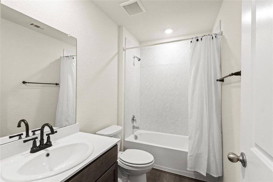 Full bathroom featuring shower / tub combo, vanity, toilet, and wood-style flooring