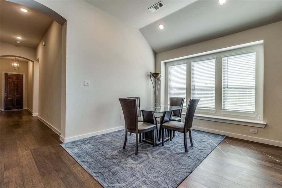 Dining space featuring vaulted ceiling and dark wood-type flooring