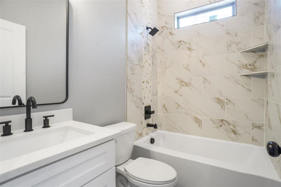 Full bathroom featuring toilet, vanity, and tiled shower / bath