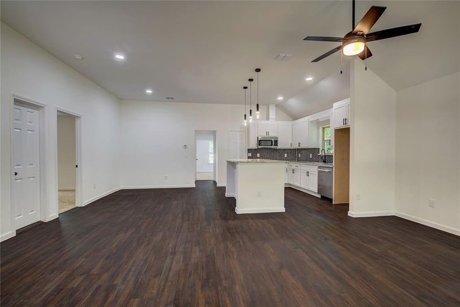 Entrance view of the kitchen featuring a center island, white cabinetry, dark wood-type flooring, appliances with stainless steel finishes, and ceiling fan