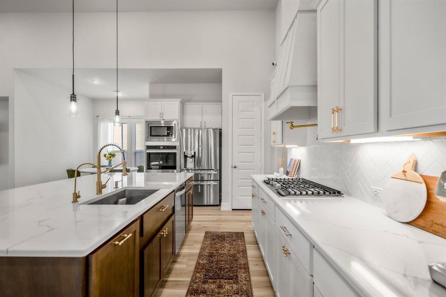 You will love the details of this kitchen! It features a large single basin sink with sleek brushed gold faucet, pot filler about cooktop, under cabinet lighting, brushed gold cabinet hardware, and quartz countertops!