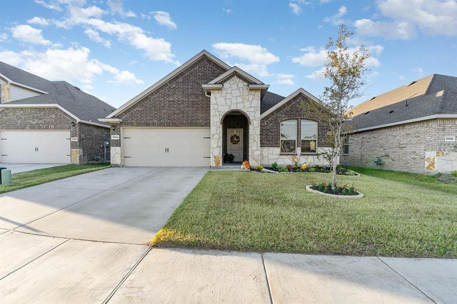 French country home featuring a garage and a front lawn