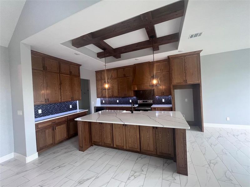 Kitchen featuring beam ceiling, electric stove, an island with sink, and tasteful backsplash