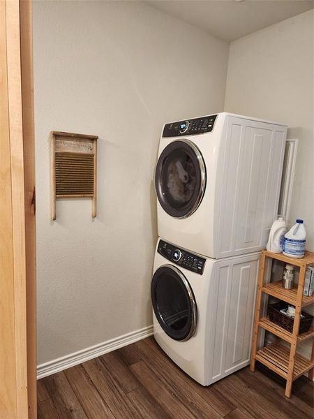 Laundry area featuring dark hardwood / wood-style floors and stacked washing maching and dryer