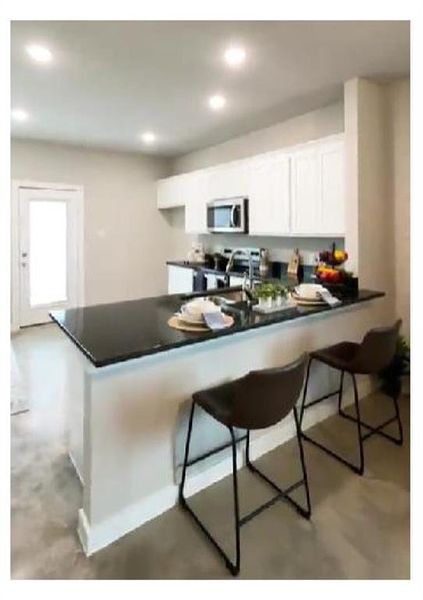 Kitchen featuring white cabinetry, kitchen peninsula, sink, and a breakfast bar area