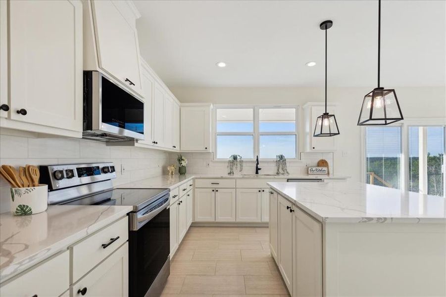 Kitchen with a wealth of natural light, stainless steel appliances, decorative light fixtures, and tasteful backsplash