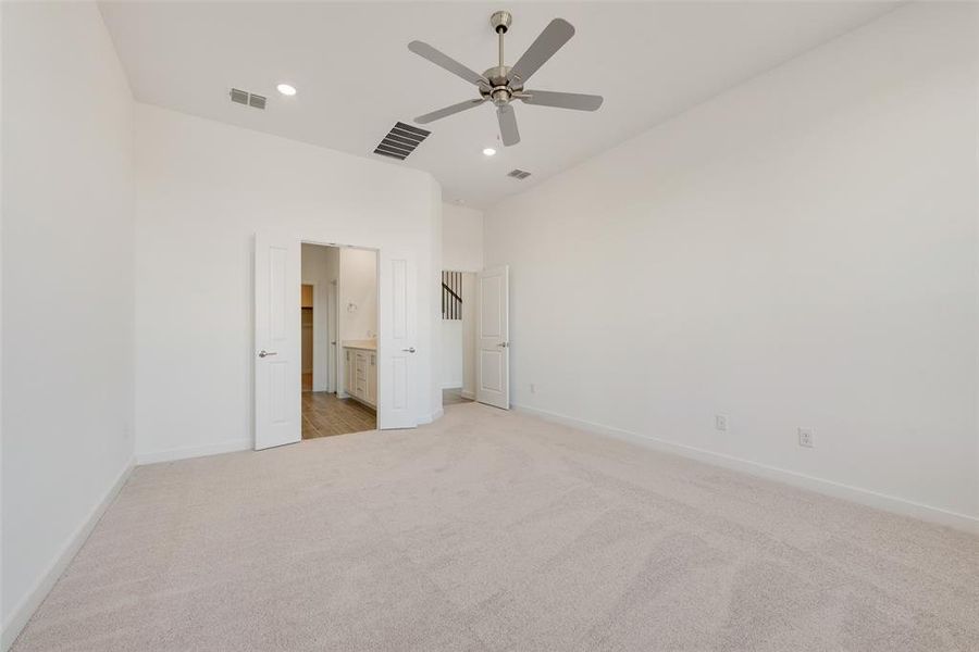 Unfurnished bedroom with light colored carpet, ceiling fan, and ensuite bath