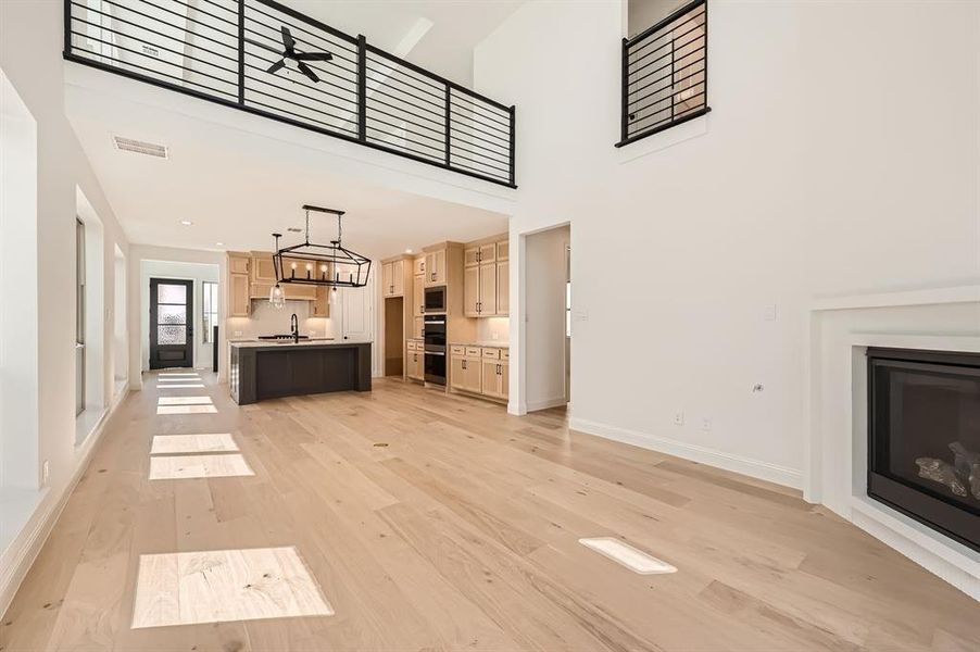 Unfurnished living room featuring a high ceiling, light hardwood / wood-style floors, and sink