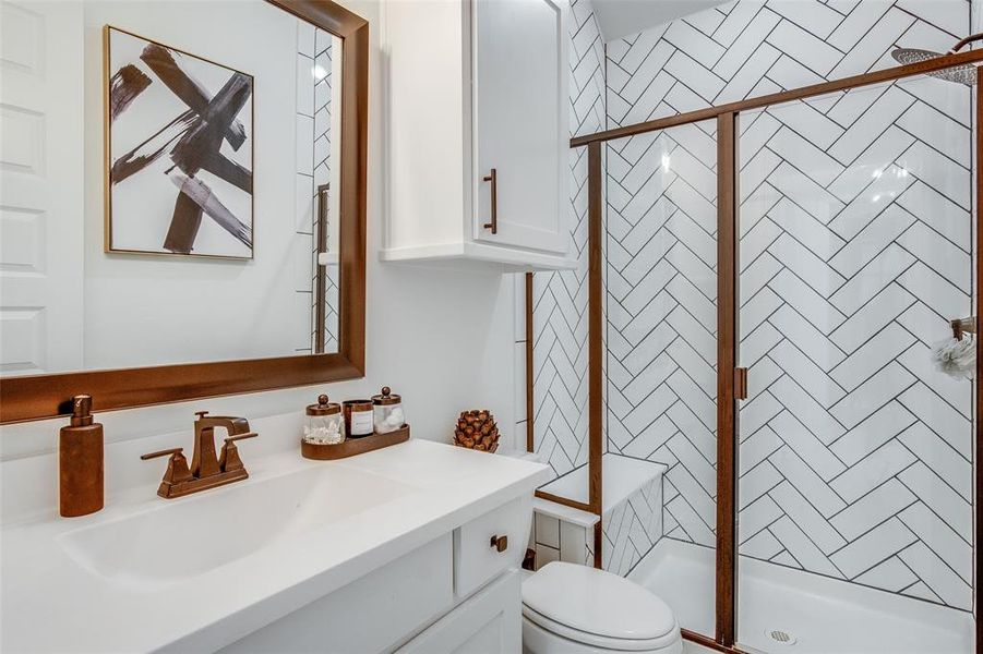 Bathroom featuring an enclosed shower, toilet, and vanity